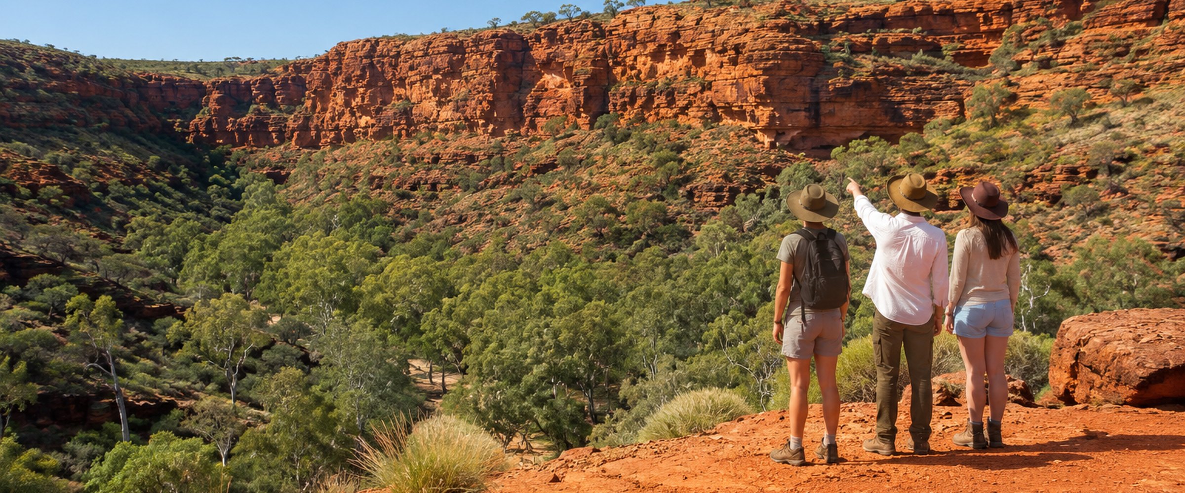 Three travellers on a red dirt lookout above an Australian outback gorge